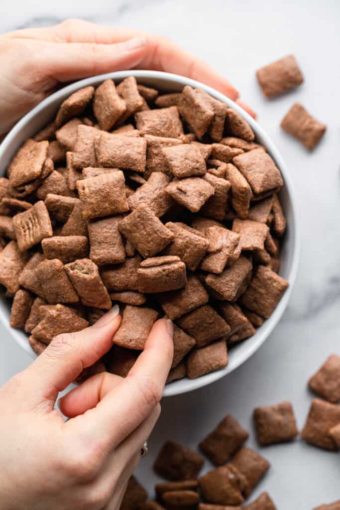 a piece of Protein Puppy Chow being picked out of a bowl
